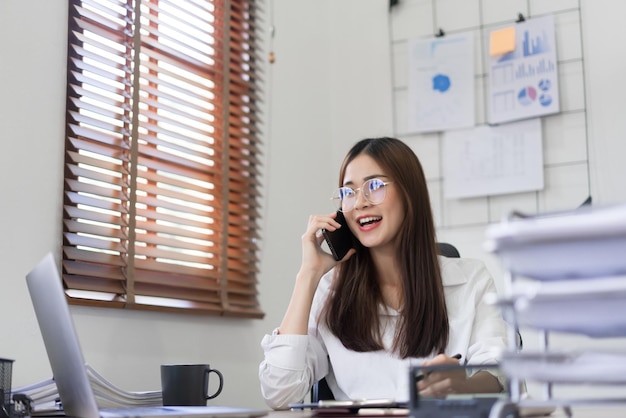 Business concept Businesswoman is talking financial data with partner on smartphone at office