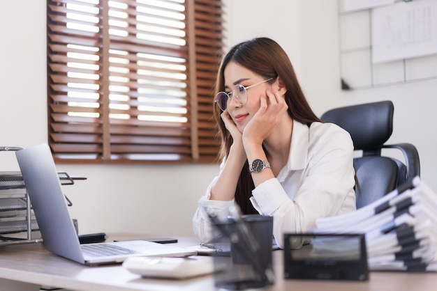 Business concept Businesswoman is touching chin on hands and reading business data on laptop