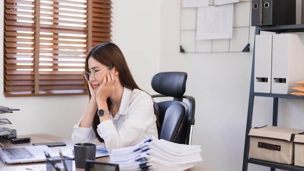 Business concept Businesswoman is touching chin on hands and reading business data on laptop