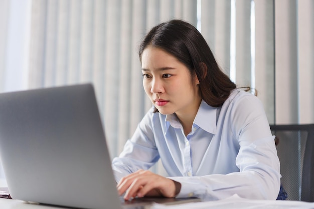 Business concept Businesswoman thoughtful about project and typing new ideas in report on laptop