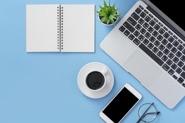 Business concept Clean bright light blue office table desk minimal style with laptop coffee and smart phone copy space top view flat lay mockup