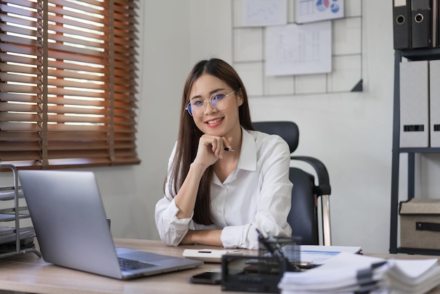 Business concept Confident businesswoman is holding pen and sitting to working in modern office