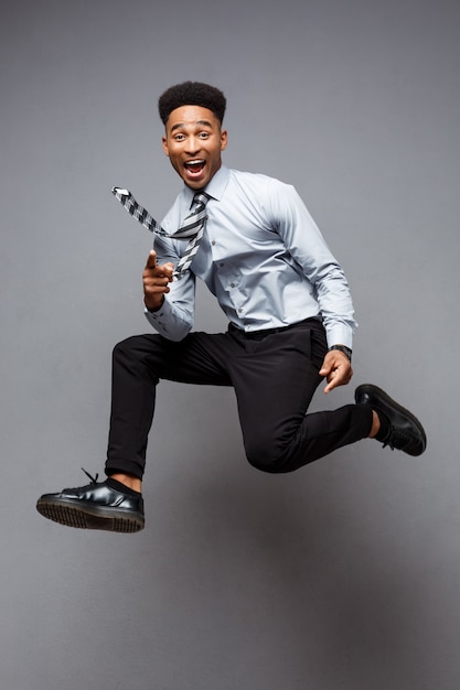 Business Concept - Full length portrait of successful african american businessman happy jumping in the office. 