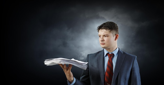 Business Concept - handsome young professional businessman holding report papers. Mixed media