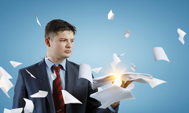 Business Concept - handsome young professional businessman holding report papers. Mixed media