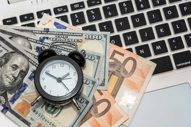 Business concept  laptop money dollars and euro with clock