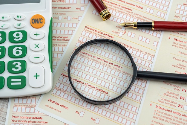 Business concept with magnifying glass and calculator on australian tax form