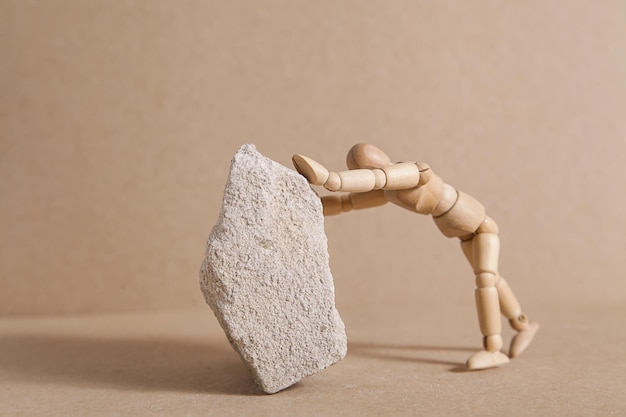 Business concept wooden man pushing large stone