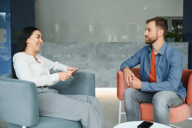 Business concept Young darkhaired woman sitting in front of mature cheerful office manager on job interview having relaxing talk about her experience and study degree