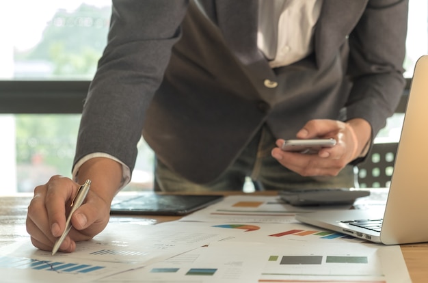 Business concepts, Man hand holding pen pointing at graph on desk