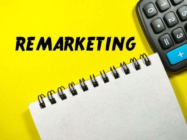 Business conceptText REMARKETING with calculator and notebook on a yellow background