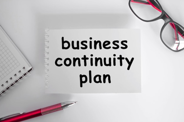 BUSINESS CONTINUITY PLAN  The notebook is on paper with text  eyeglasses Concept photo