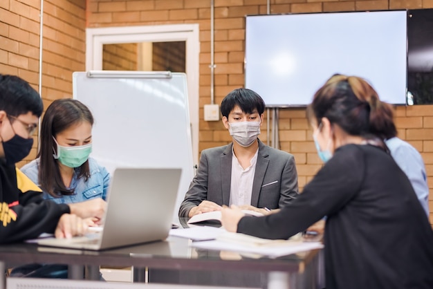 Business cooperation : Young asian male coach or speaker make flip chart presentation to diverse businesspeople at meeting in office. Male tutor or trainer present project to diverse colleagues.