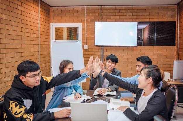 Business cooperation : Young asian male coach or speaker make flip chart presentation to diverse businesspeople at meeting in office. Male tutor or trainer present project to diverse colleagues.