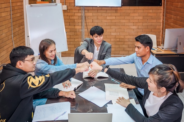 Business cooperation : Young asian male coach or speaker make flip chart presentation to diverse businesspeople at meeting in office. Male tutor or trainer present project to diverse colleagues.