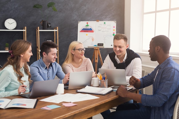 Business corporate meeting of multiethnic team. Young cheerful people brainstorming, discussing new startup project in office, copy space