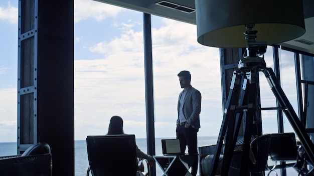 Business couple silhouettes thinking at marine view Coworkers discussing deal