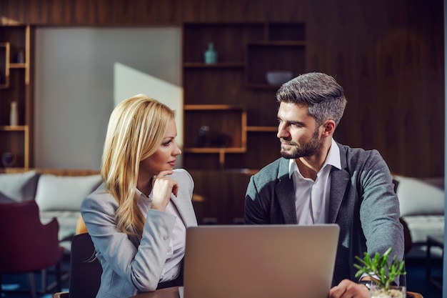 Business couple sitting in a cafe and having a business talk. There is a laptop on a table. Business meeting, technology, cooperation