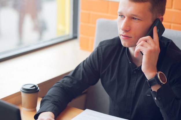 Business of a cup of coffee and enjoy your work in a coffee shop talking on the phone