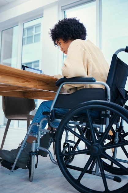 Business desk and woman in wheelchair in office working on project report and proposal Corporate professional and person with disability with technology for internet research and browse online