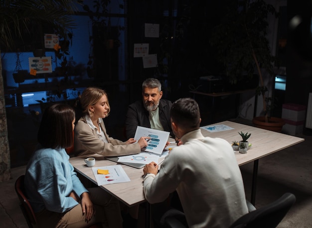 Business discussion in contemporary evening office of team they are sitting around the table and lis