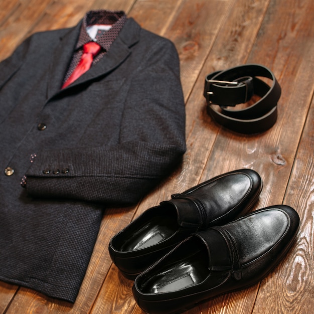 Business dress code. Male suit with shoes and belt on dark wooden.