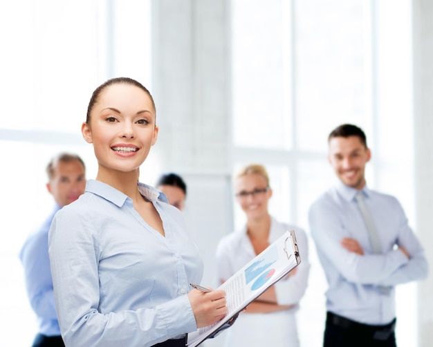 business and education concept - friendly young smiling businesswoman with clipboard and pen