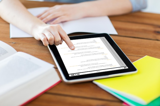 business, education, technology and programming concept - close up of student woman with coding on tablet pc computer screen and notebook at home