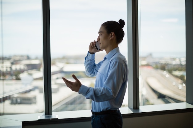 Business executive talking on mobile phone in corridor