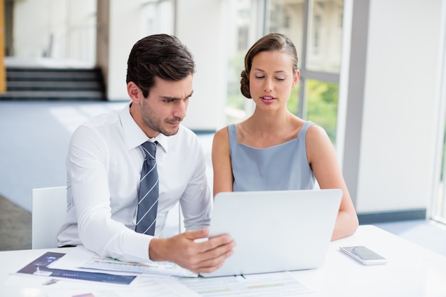 Business executives discussing over laptop