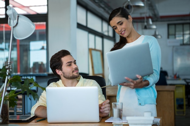 Business executives discussing over laptop