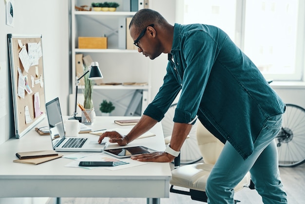 Business expert. Handsome young African man in shirt using laptop while standing in the office