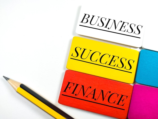 Business and finance concept Text BUSINESSSUCCESSFINANCE on colorful wooden board and pencil on white background