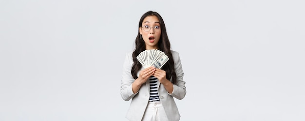 Business finance and employment entrepreneur and money concept Amazed and speechless young asian businesswoman earn first paycheck for selling house holdin cash and stare astonished