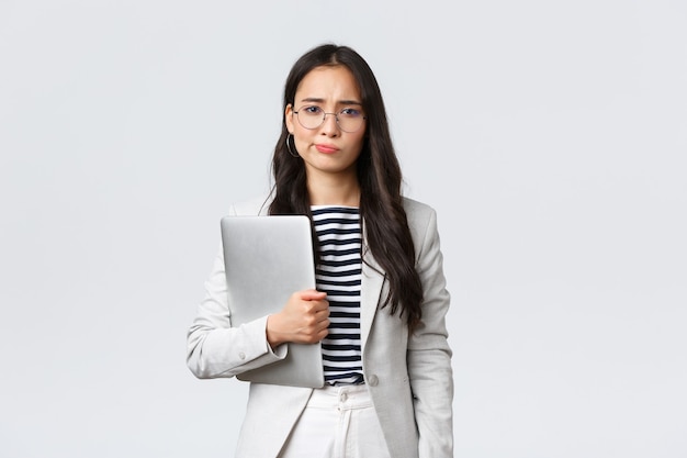 Business, finance and employment, female successful entrepreneurs concept. Sad and doubtful businesswoman having hesitations about meeting, smirk displeased, holding laptop