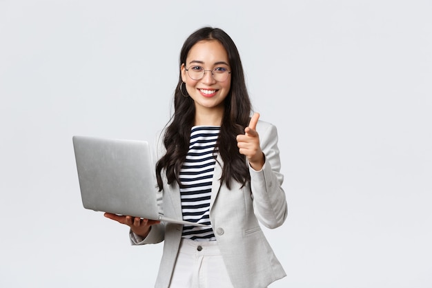 Business, finance and employment, female successful entrepreneurs concept. Smiling pleased businesswoman praise coworker who made good point, pointing finger camera satisfied, hold laptop