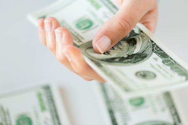 business, finance, saving, banking and people concept - close up of woman hand counting us dollar money