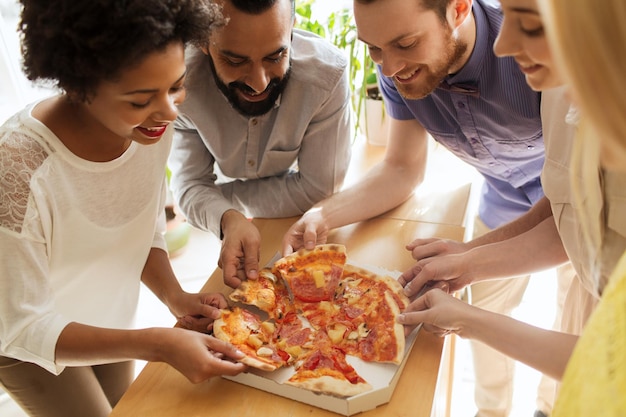 business, food, lunch and people concept - happy business team eating pizza in office