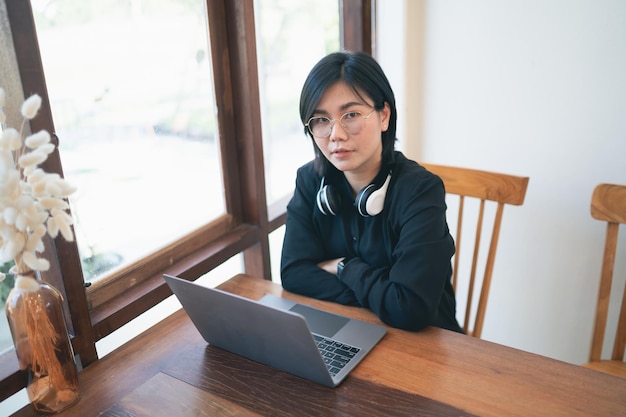 Business freelance entrepreneur woman with white headphone working typing keyboard on laptop and on wooden table at the cafe coffee shop Business technology concept