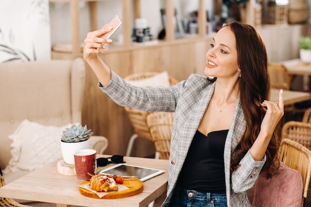 A business Girl is sitting in a cafe and taking a selfie