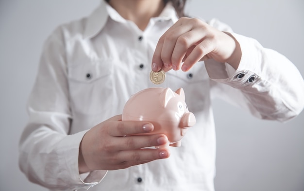 Business girl putting coin to piggy bank. Saving money