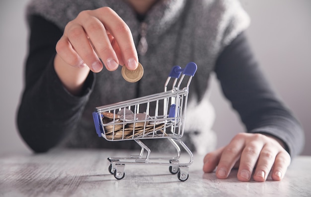 Business girl putting coin to shopping cart. Shopping concept