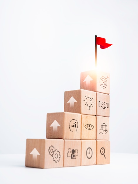 Business goal with growth success process for Leadership concept. Red flag on the top of wooden cube blocks as a stair step with up arrow sign strategy icon on white background, vertical style.