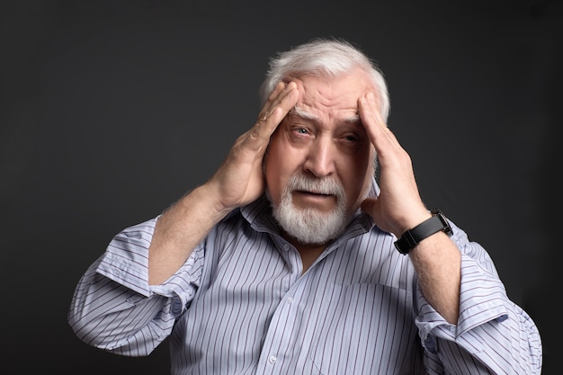 Business, gray-haired man holding his head with two hands. Headache