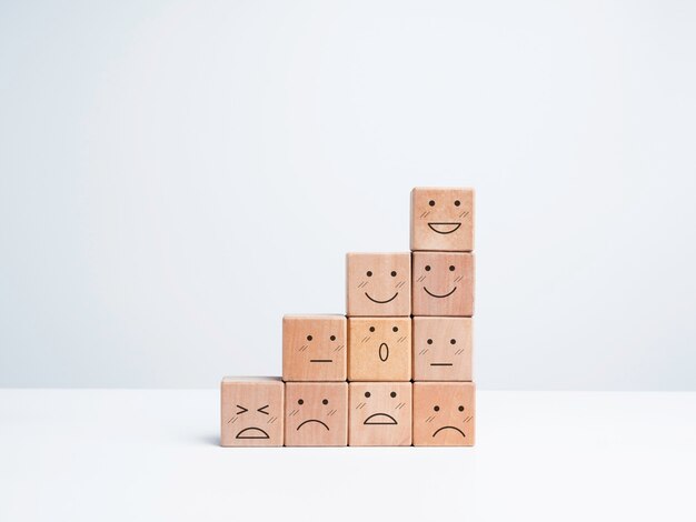 Photo business growth steps with happy and sad emotions on emoticon faces arrange on wooden blocks isolated on white background, minimal style. satisfaction, evaluation, rating survey concept.