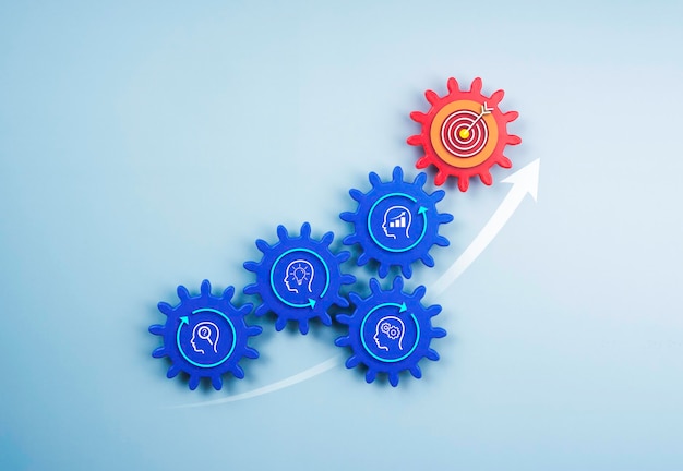 Business growth and success, solution, management, teamwork, cooperation, innovation, leadership. Target icon on red gear and business strategy icon on blue cogwheels with up arrow on blue background.