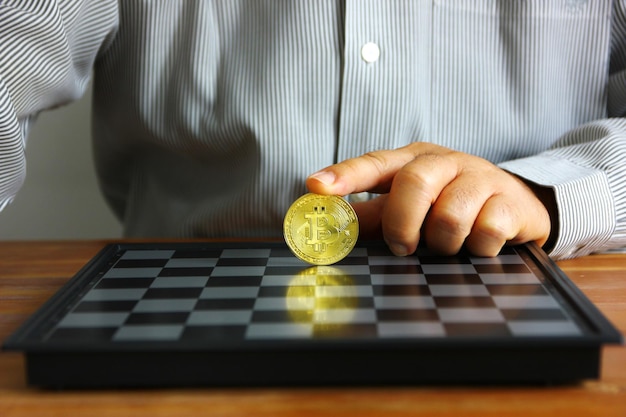 Business hand put on index finger on bit coin on chess board