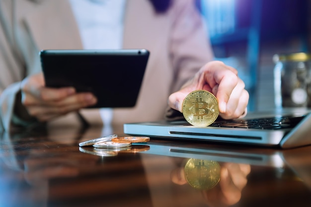 Business hand using smartphone and laptop with golden bitcoin