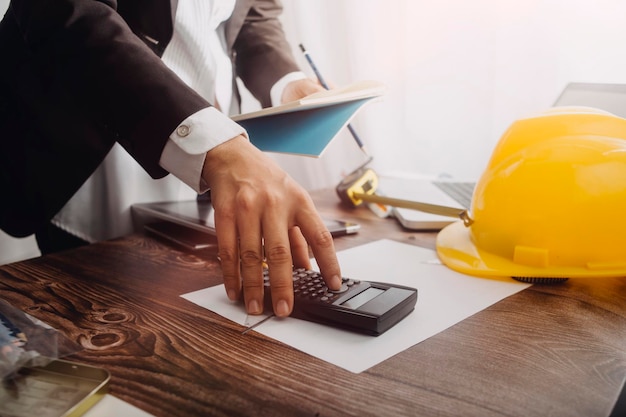 Business hand working and laptop with on on architectural project at construction site at office desk in office