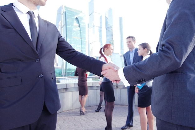 Business handshake the deal Is finalized by group of people outside